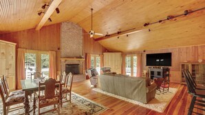 A spacious living room with a wooden ceiling, a fireplace, a television, and a dining area with a table and chairs. - Private Walterboro Estate w/ Deck + Fire Pit! (Walterboro)