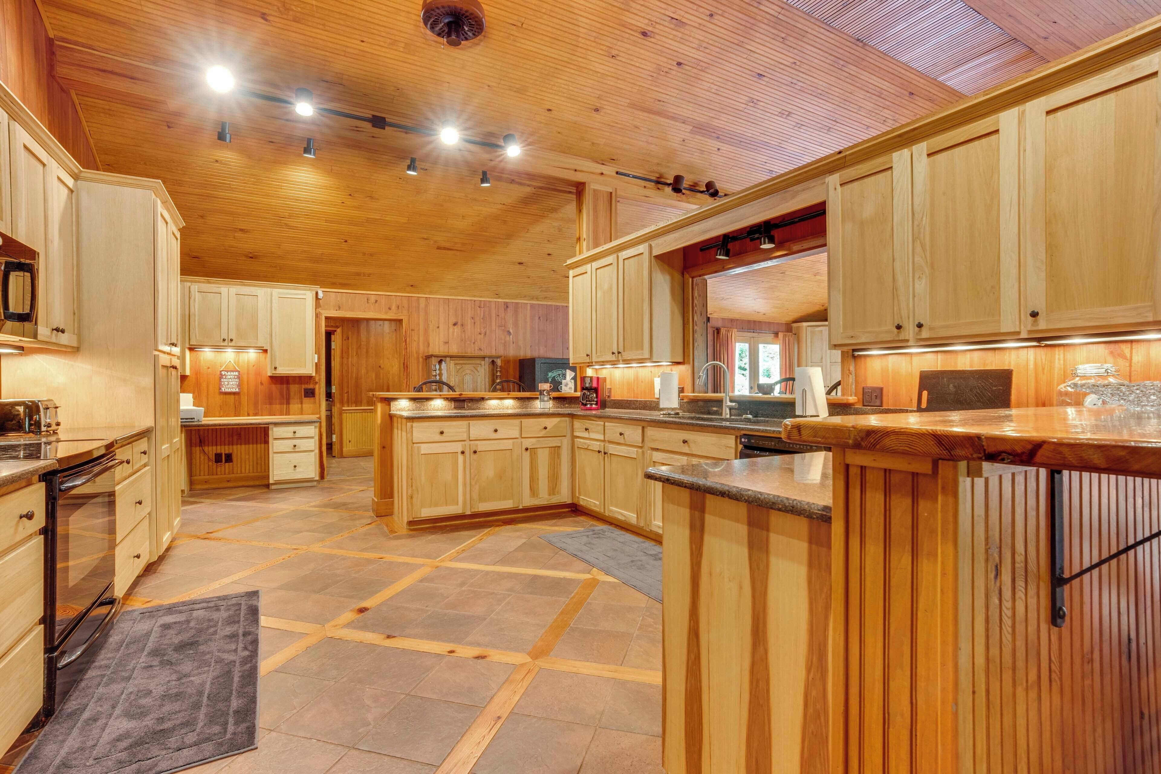 A spacious kitchen with wooden cabinets, a large island, and a tiled floor.