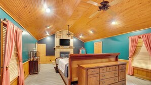 A bedroom with a wooden ceiling, a bed, a dresser, and a television mounted above the fireplace. - Private Walterboro Estate w/ Deck + Fire Pit! (Walterboro)
