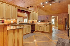 Une cuisine spacieuse avec des meubles en bois, un îlot central et un sol carrelé.