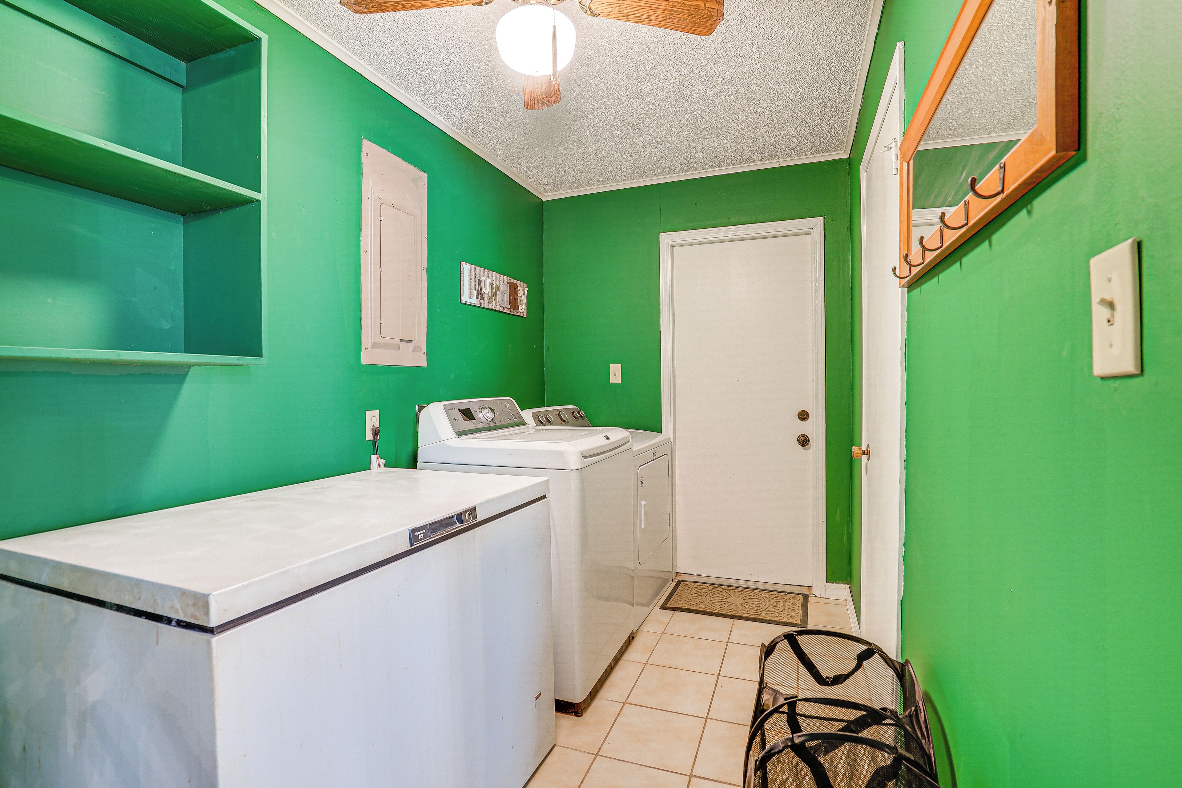 Une buanderie avec des murs verts, une porte blanche et un ventilateur de plafond.