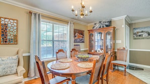 A dining room with a wooden table, chairs, a chandelier, and a cabinet. - Charming Retreat w/ Patio: Near Grambling/ruston! (Simsboro)
