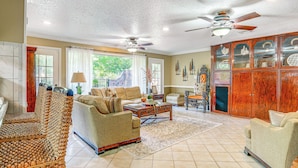 A spacious living room with a high ceiling, two ceiling fans, a large wooden cabinet, and a comfortable seating area with a sofa and chairs. - Charming Retreat w/ Patio: Near Grambling/ruston! (Simsboro)