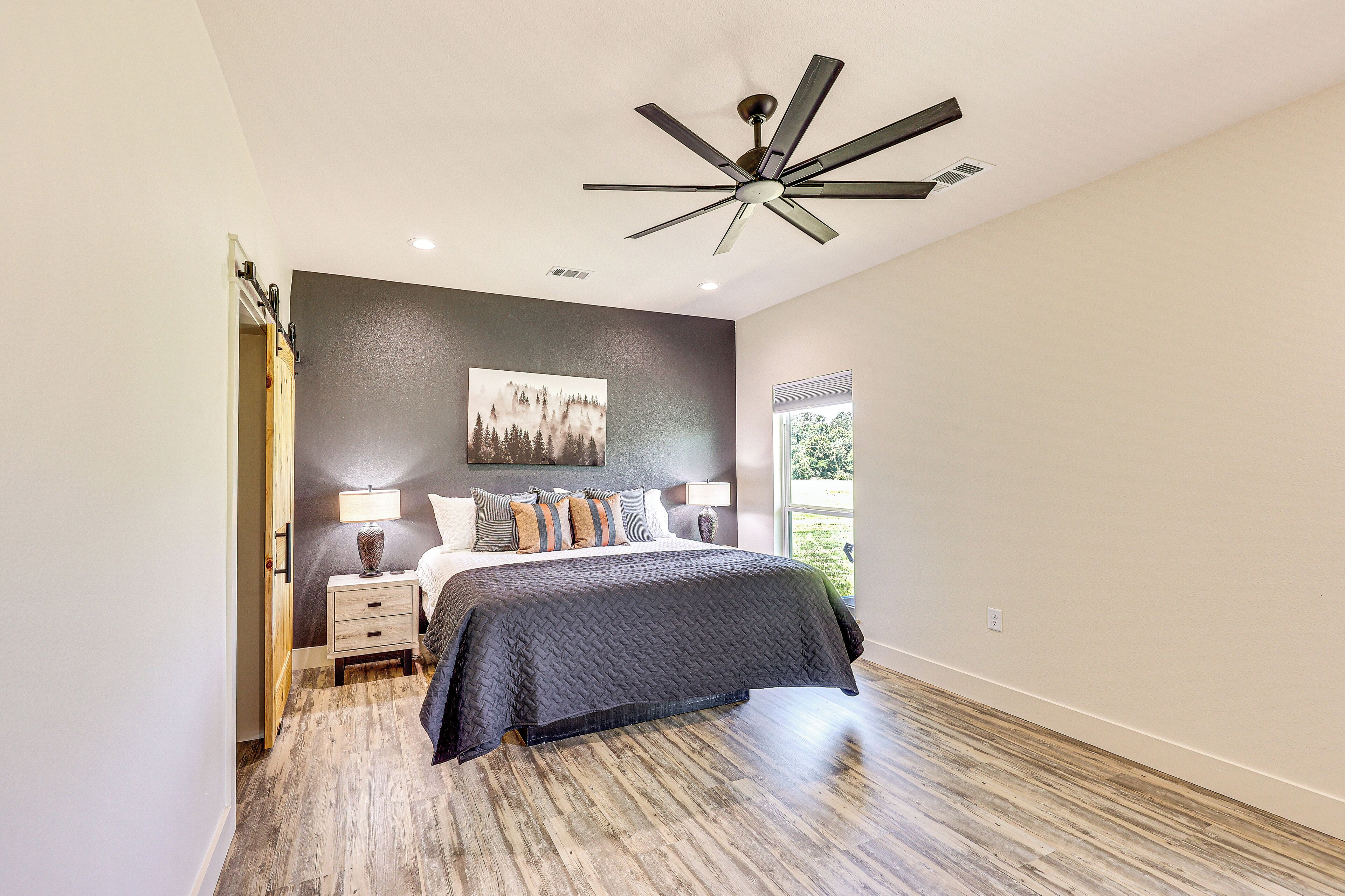 A bedroom with a bed, nightstands, a ceiling fan, and a window.
