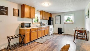 Une cuisine moderne avec des meubles en bois, un four à micro-ondes encastré et un coin repas comprenant une table et des chaises.