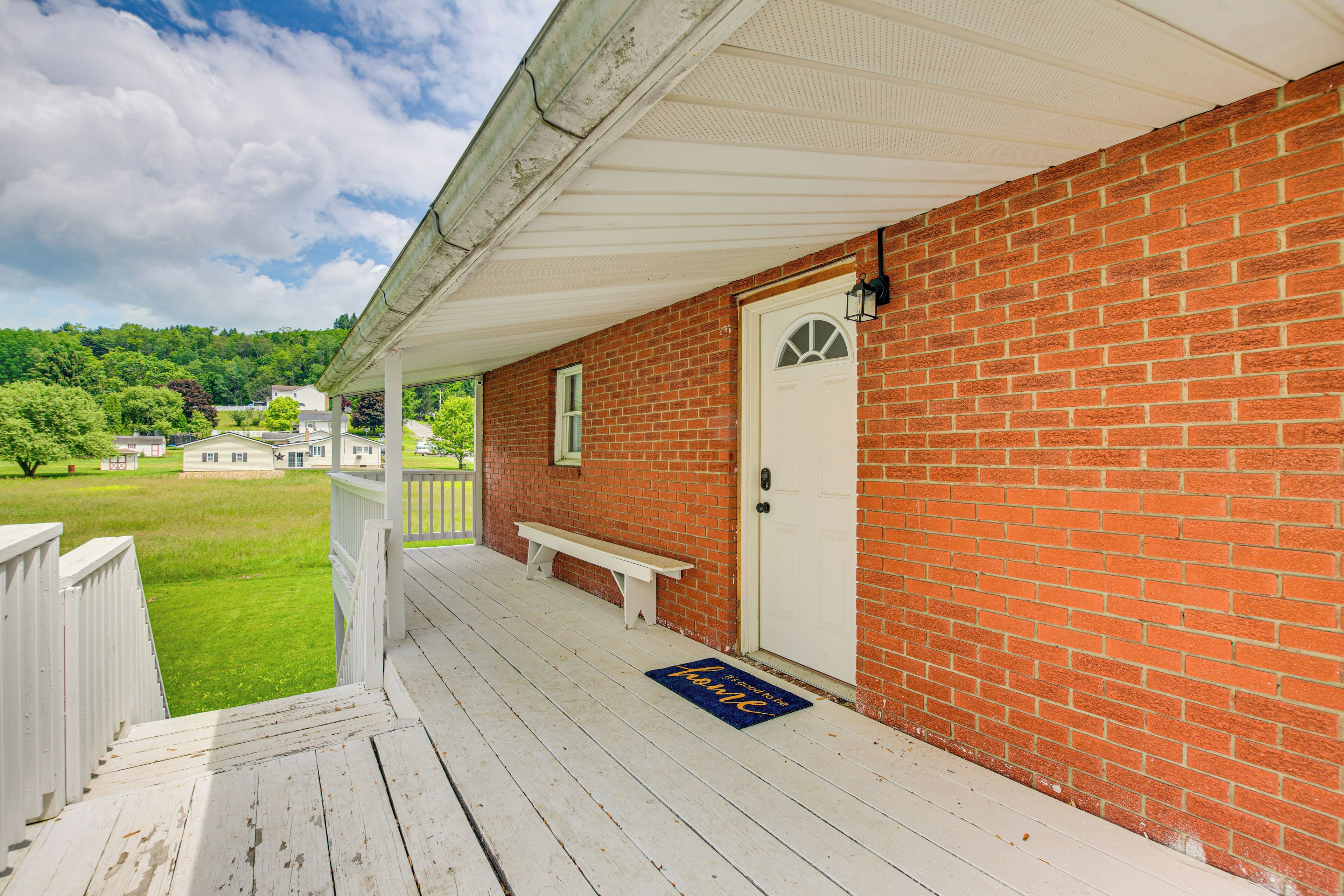 A brick building with a white porch, a white door, and a bench.