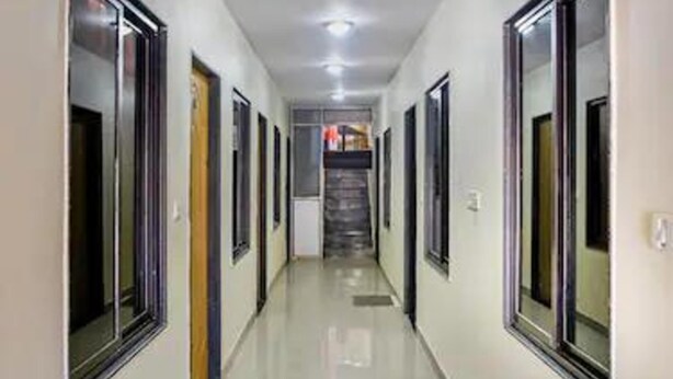 A corridor with doors on both sides, leading to a staircase. - Hotel Padmawati By GRB Stays (Abu Road)