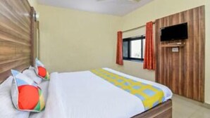 A hotel room with a bed, a ceiling fan, a TV mounted on the wall, and a window with curtains. - Hotel Padmawati By GRB Stays (Abu Road)