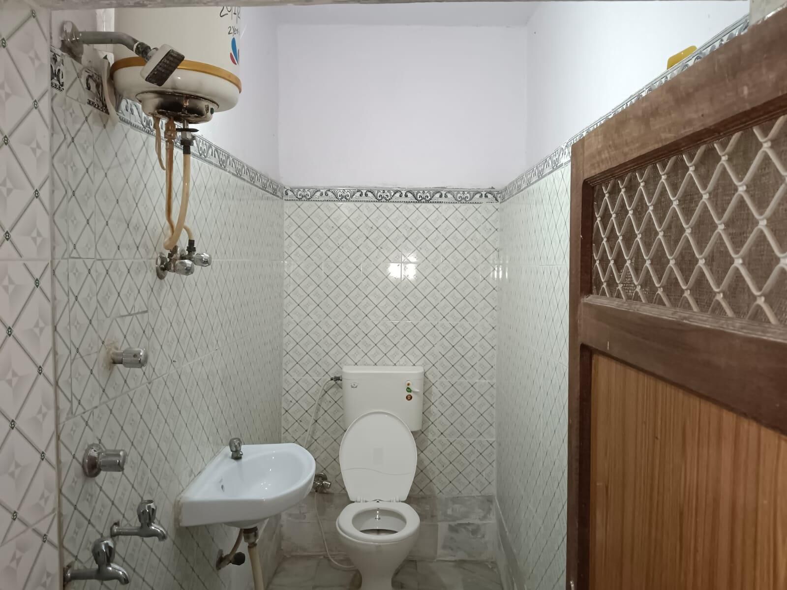 A small bathroom with a toilet, sink, and shower.