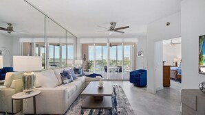 A modern living room with a sofa, coffee table, and a large mirror. - 🌴Great Water Views, Fabulous Location-Palm Harbor #403🌴 (Fort Myers Beach)