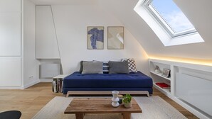 A modern loft bedroom with a skylight, a blue sofa, and a wooden coffee table. - Miel, 1BR/1BA, 3 people (París)