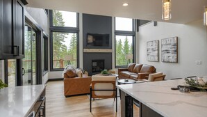 A modern kitchen with a large island, a fireplace, and a dining area with leather sofas.