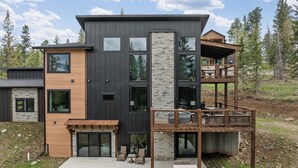 A modern two-story house with a stone facade, large windows, and a wooden deck.