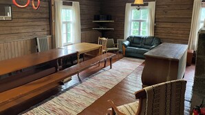 Un interno rustico di una baita di legno, con un tavolo da pranzo, panche, un divano e un camino.