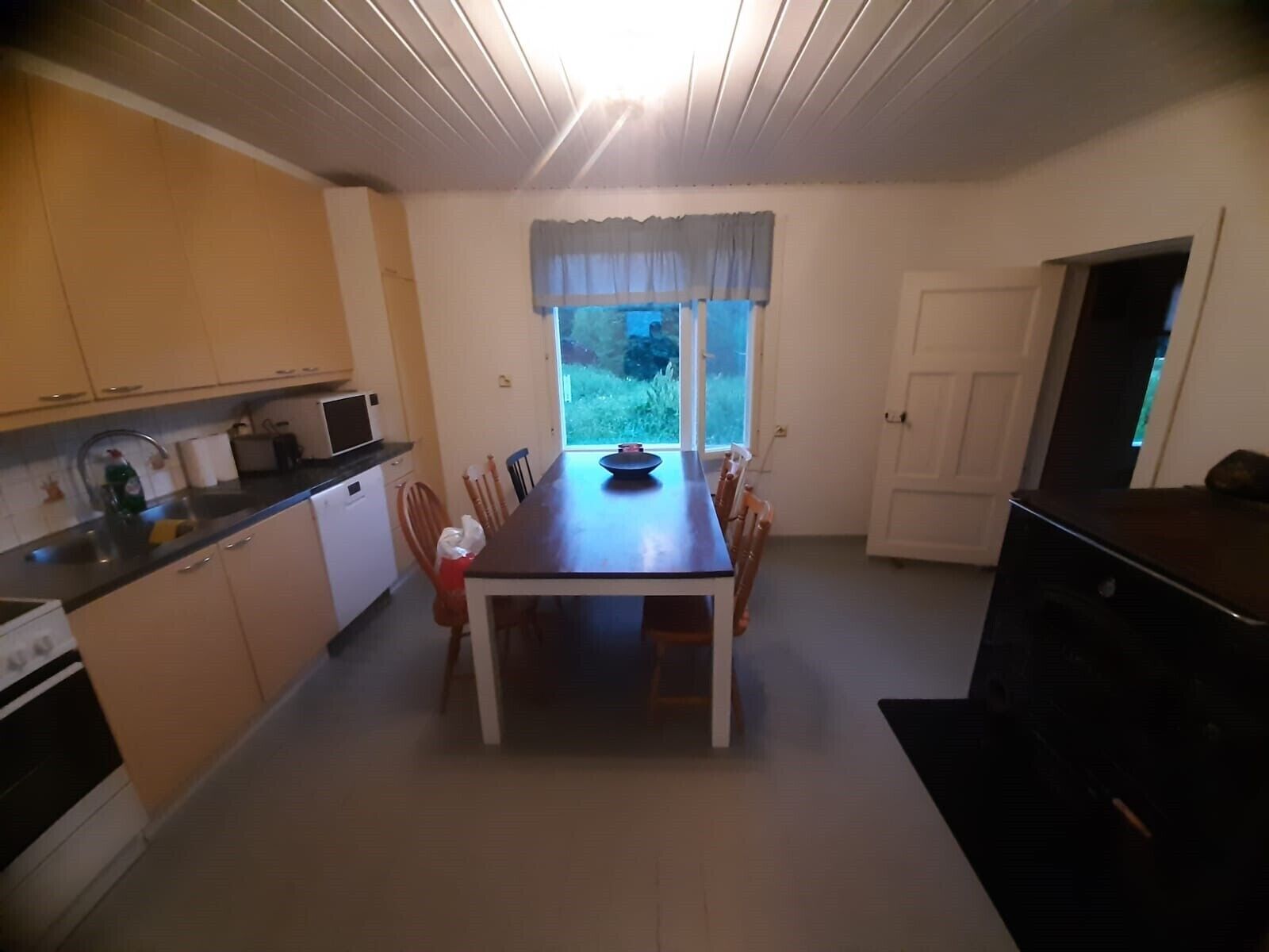 Une cuisine de taille réduite comprenant une table à manger, des chaises, une fenêtre avec des rideaux et une porte.