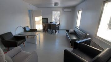 Een moderne woonkamer met een bank, een salontafel en een eethoek met stoelen en een tafel.
