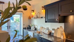 A modern kitchen with dark cabinetry, a built-in oven, and a countertop with a coffee maker and toaster.