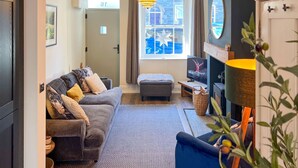 A cozy living room with a grey sofa, a blue armchair, a fireplace, and a large window with a star decoration.
