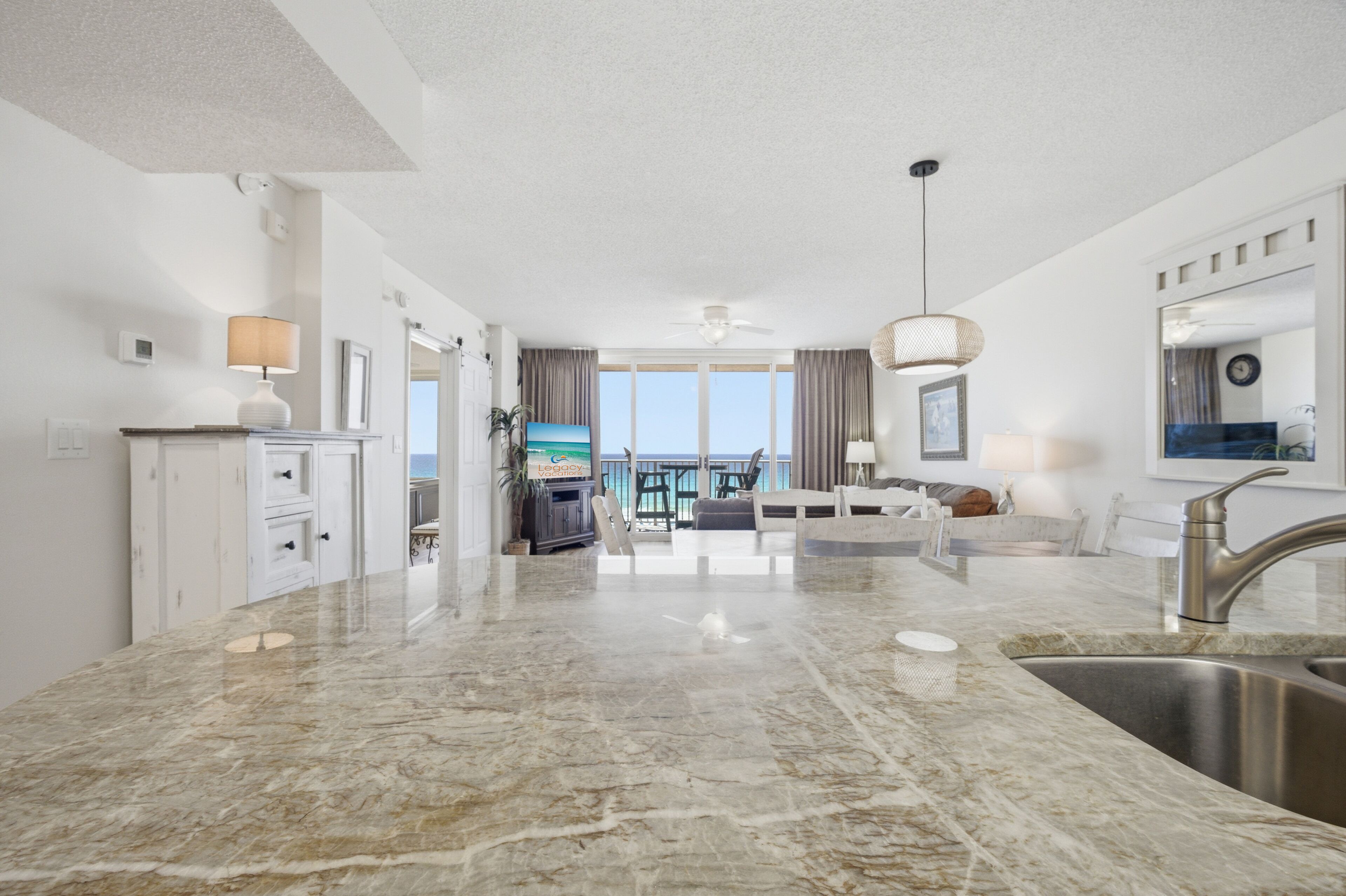 A modern kitchen with a marble countertop, a built-in sink, and a dining area with a view.