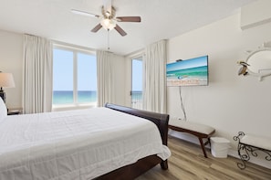 Une chambre d’hôtel avec un lit, un ventilateur de plafond, une télévision, un banc et une vue sur l’océan.