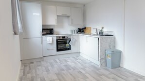 A compact kitchen with white cabinets, a microwave, an oven, and a small trash bin. - 2 Bedrooms-4 Guests-babycot-wifi-freeparking (London)