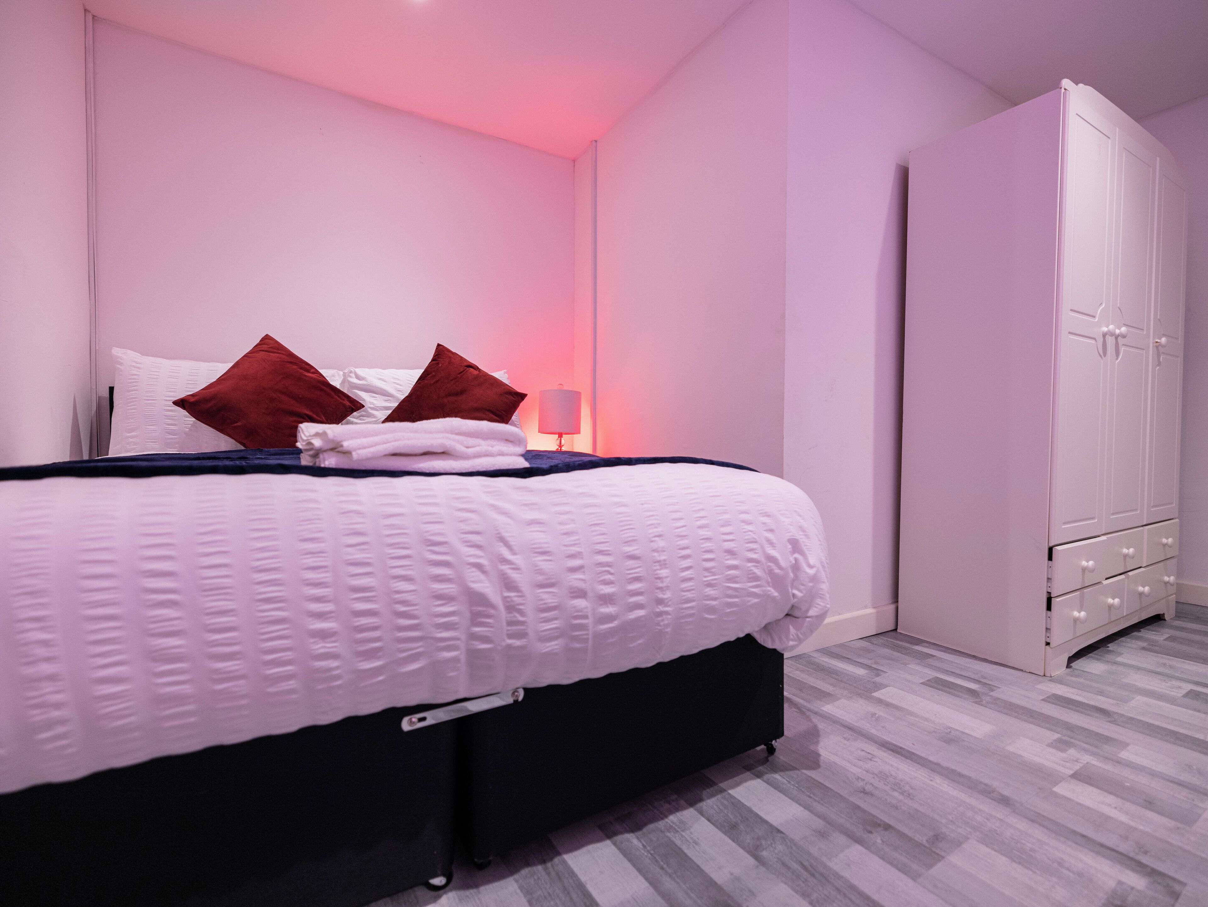 Ein Schlafzimmer mit Bett, Kissen, einer Nachttischlampe und einem Kleiderschrank.