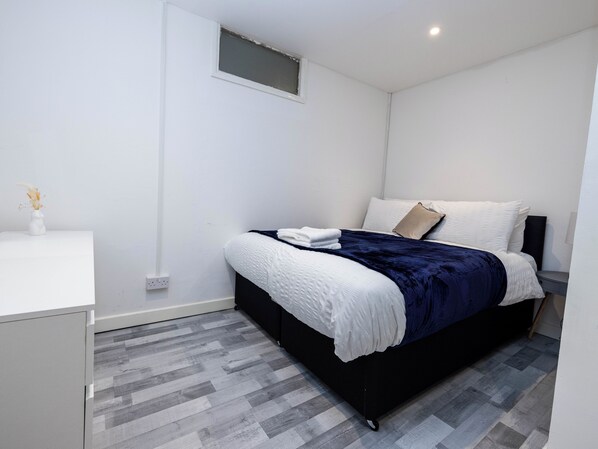 A modern bedroom with a bed, bedside table, and a small window. - 1 Bed-4guests-sofabed-wifi-closetocity-parking (London)
