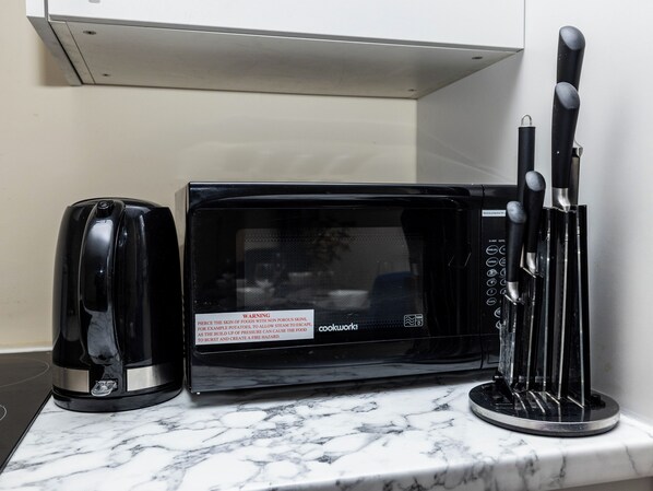 A kitchen with a microwave, toaster, and knife set on a marble countertop. - 1 Bed-4guests-sofabed-wifi-closetocity-parking (London)
