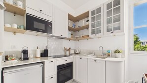 A modern kitchen with white cabinets, a Bosch microwave, a built-in oven, and a window with a view. - Flat in the town centre - 270m  l'Ecluse beach (Dinard)