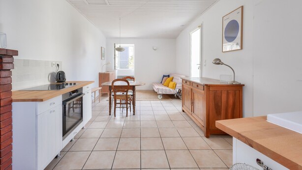 A kitchen with white cabinets, a wooden countertop, and a dining area with a table and chairs. - Quiet location - 5min from La Terrière beach (La Tranche-sur-Mer)