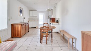 A spacious kitchen with a wooden dining table, chairs, and a bench. - Quiet location - 5min from La Terrière beach (La Tranche-sur-Mer)