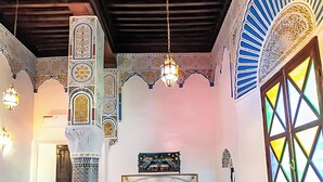 A room with a bed, a chair, a table, and a decorative column. - Riad Mounana luxurious palace & spa  (Fes)