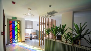 A hotel lobby with a colorful stained glass door, a reception desk, and potted plants. - Lina Guest House (Ayvalik)