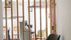 A room with a wooden partition, a green chair, a black chair, and a small table with a plant. - Lina Guest House (Ayvalik)