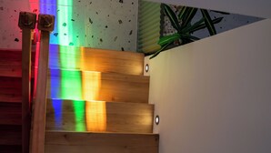 A wooden staircase with a modern design, featuring a light fixture at the top and a plant on the right side. - Lina Guest House (Ayvalik)