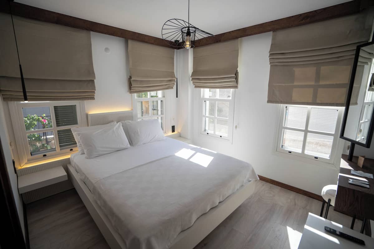 A bedroom with a large bed, built-in nightstands, a desk, and a chair.