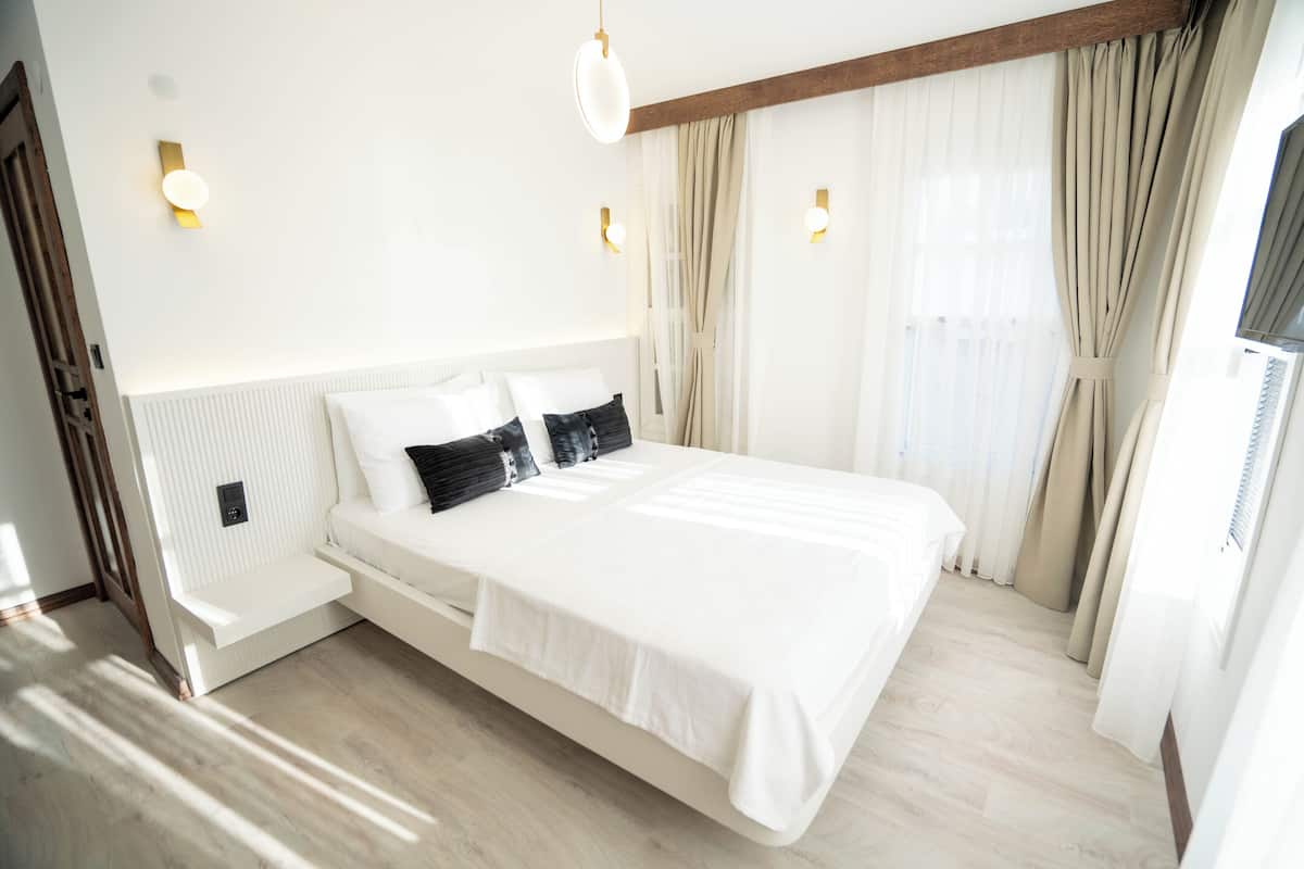 A modern bedroom with a large bed, bedside tables, and a view of the outdoors.