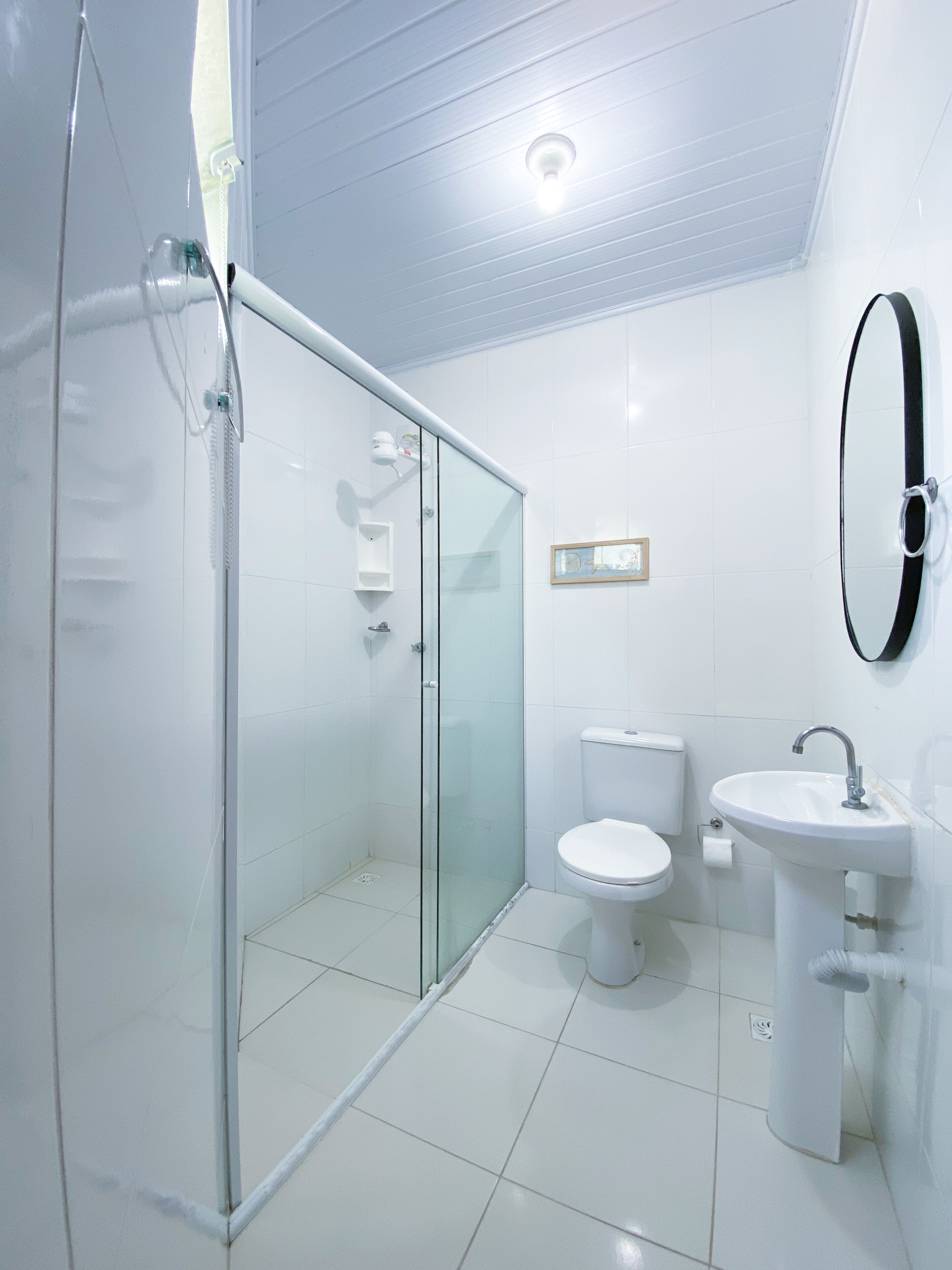 A modern bathroom with a glass-enclosed shower, a toilet, and a sink.