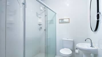 A modern bathroom with a glass-enclosed shower, a toilet, and a sink.
