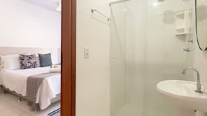 Et moderne badeværelse med brusekabine i glas, et konsolbord som håndvask og en synlig brusehoved.