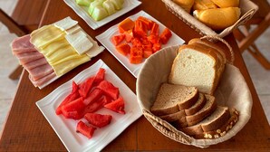Et bord dækket med forskelligt mad, herunder skiveskåret brød, ost, skinke, vandmelon og gulerødder.