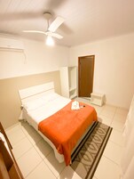 Een slaapkamer met een bed, een plafondventilator, een kledingkast en een klein nachtkastje.