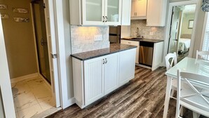 A modern kitchen with white cabinetry, a marble countertop, and a wooden floor. - Updated Condo at The Lookout in Ogunquit (Ogunquit)
