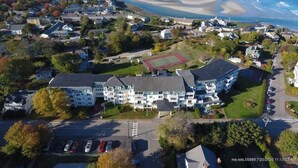 An aerial view of a coastal residential area with houses, a beach, and a large building with a tennis court. - Updated Condo at The Lookout in Ogunquit (Ogunquit)