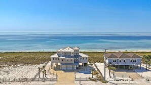 Une maison à deux étages située en bord de mer, dotée d’un grand garage et d’un patio couvert.