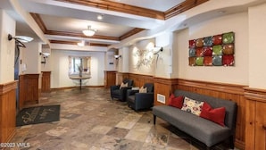 Eine großzügige Lobby mit Holzboden, einer Rezeption, einer Sitzecke mit Sofa und Sesseln sowie einem farbenfrohen Wandbild.