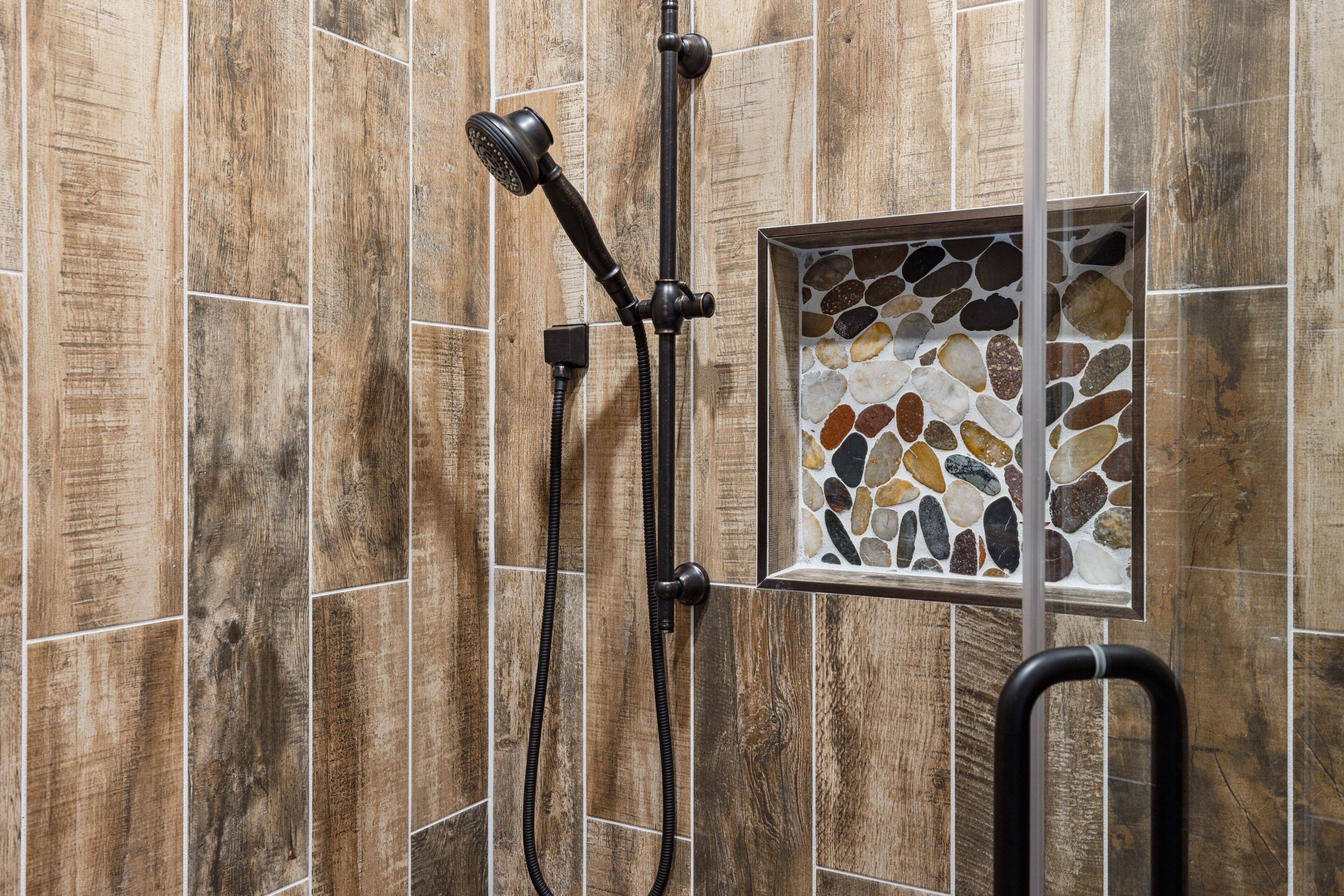 Chuveiro com azulejos de madeira e decoração em mosaico.