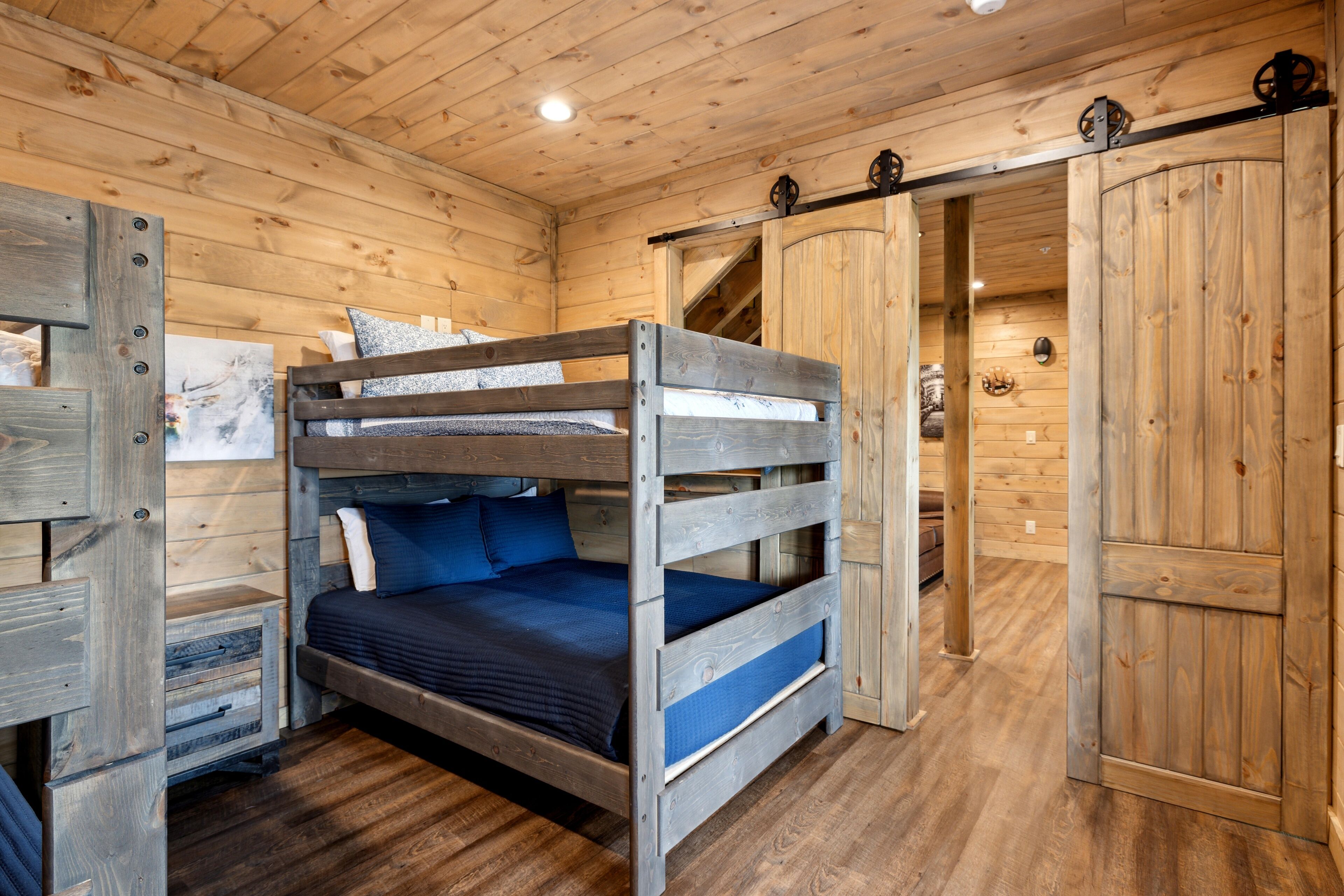 Habitación tipo cabaña de madera con literas, un armario y suelo de madera.