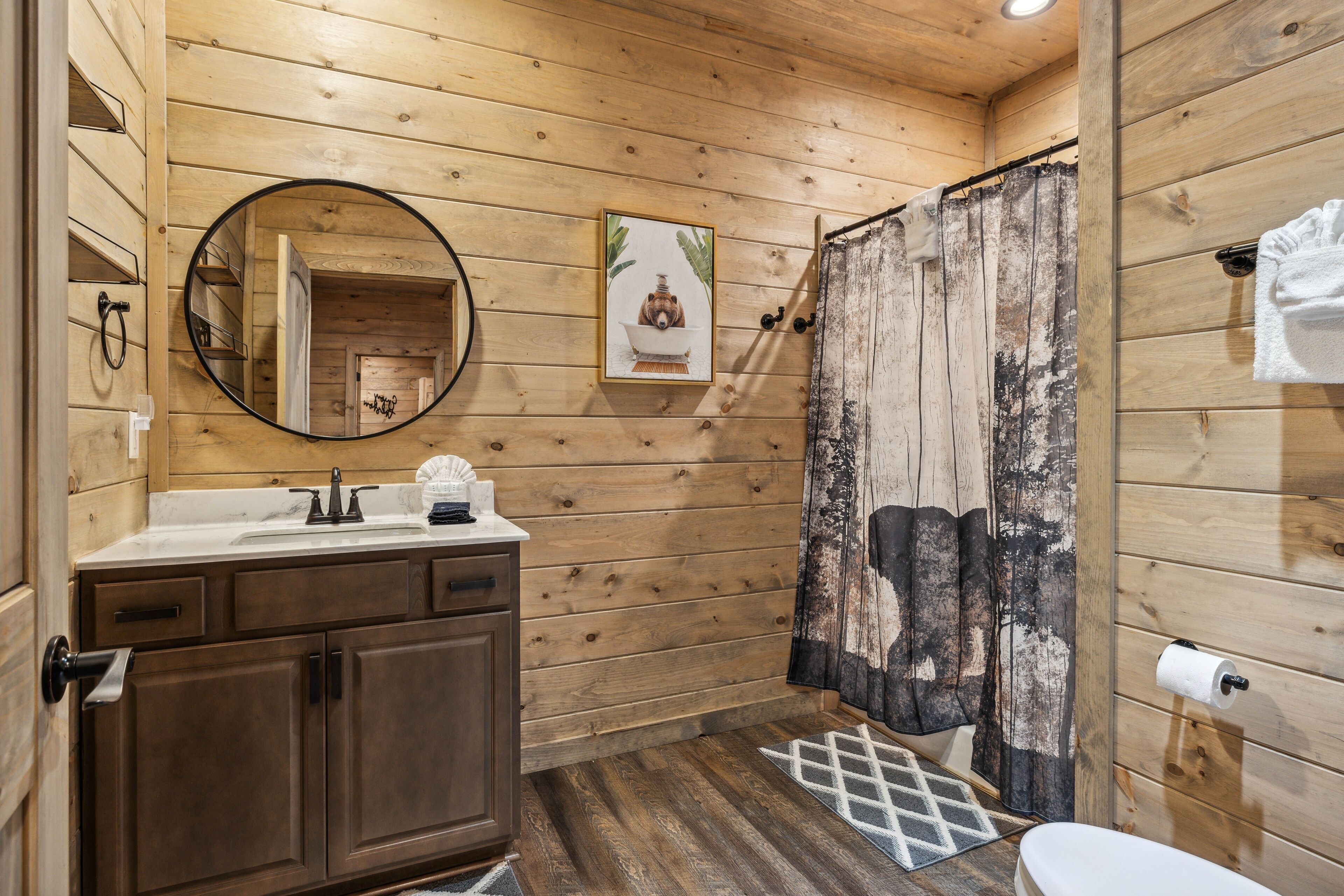 Baño de cabaña de madera con lavamanos, espejo e inodoro.
