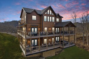 A multi-story wooden cabin with a balcony on the ground floor and a covered patio on the upper level.